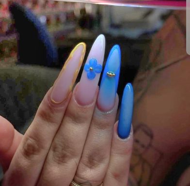 Colorful long nails featuring pink, blue, and floral designs with embellishments.